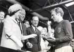 This photograph shows the Queen presenting the 1966 World Cup to Bobby Moore, captain of the victorious England team. The match was played between England and West Germany on 30 July 1966 at Wembley Stadium.